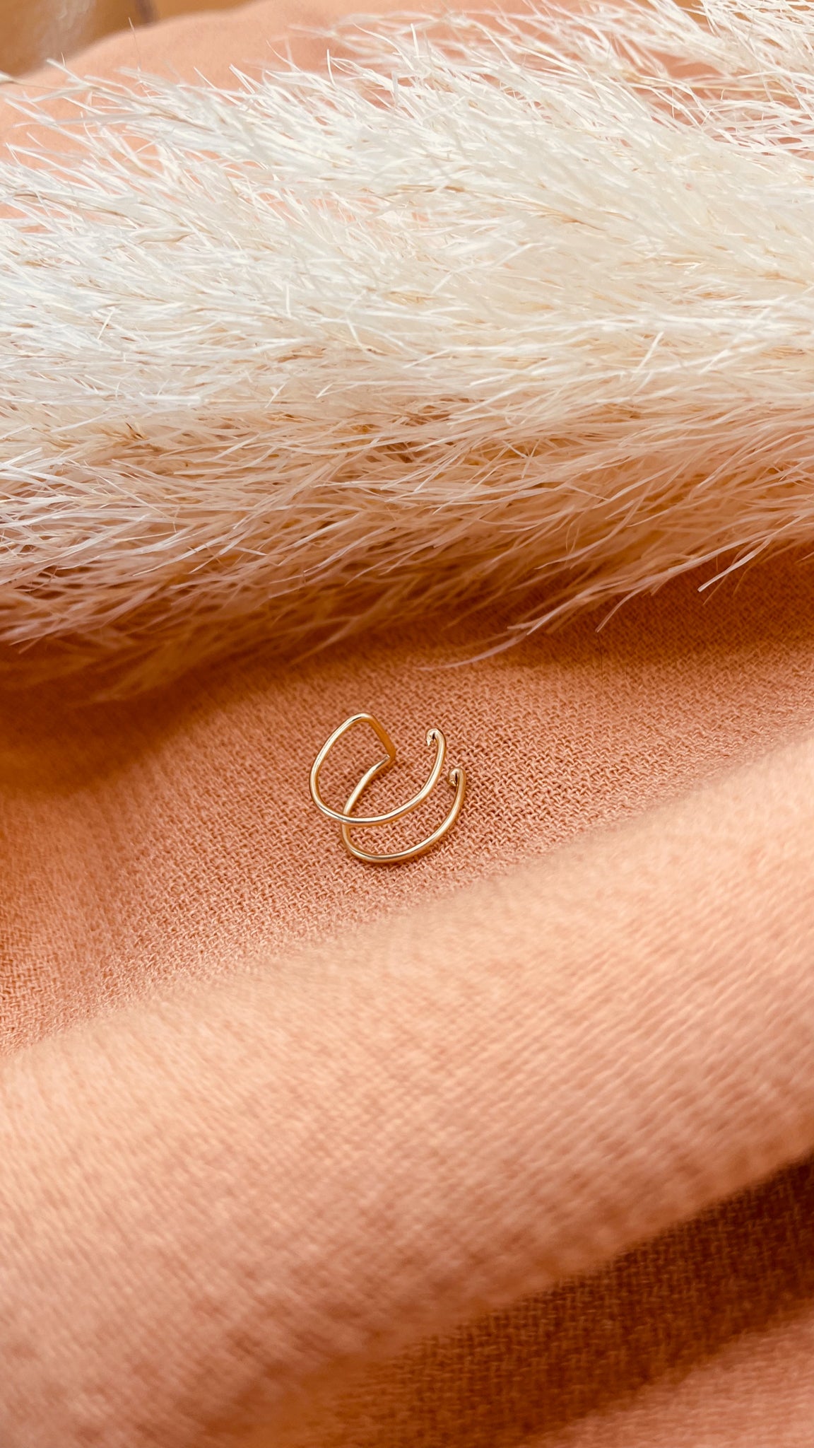 Faux piercing d'oreille en fil gold filled doré sur fond de tissu orange